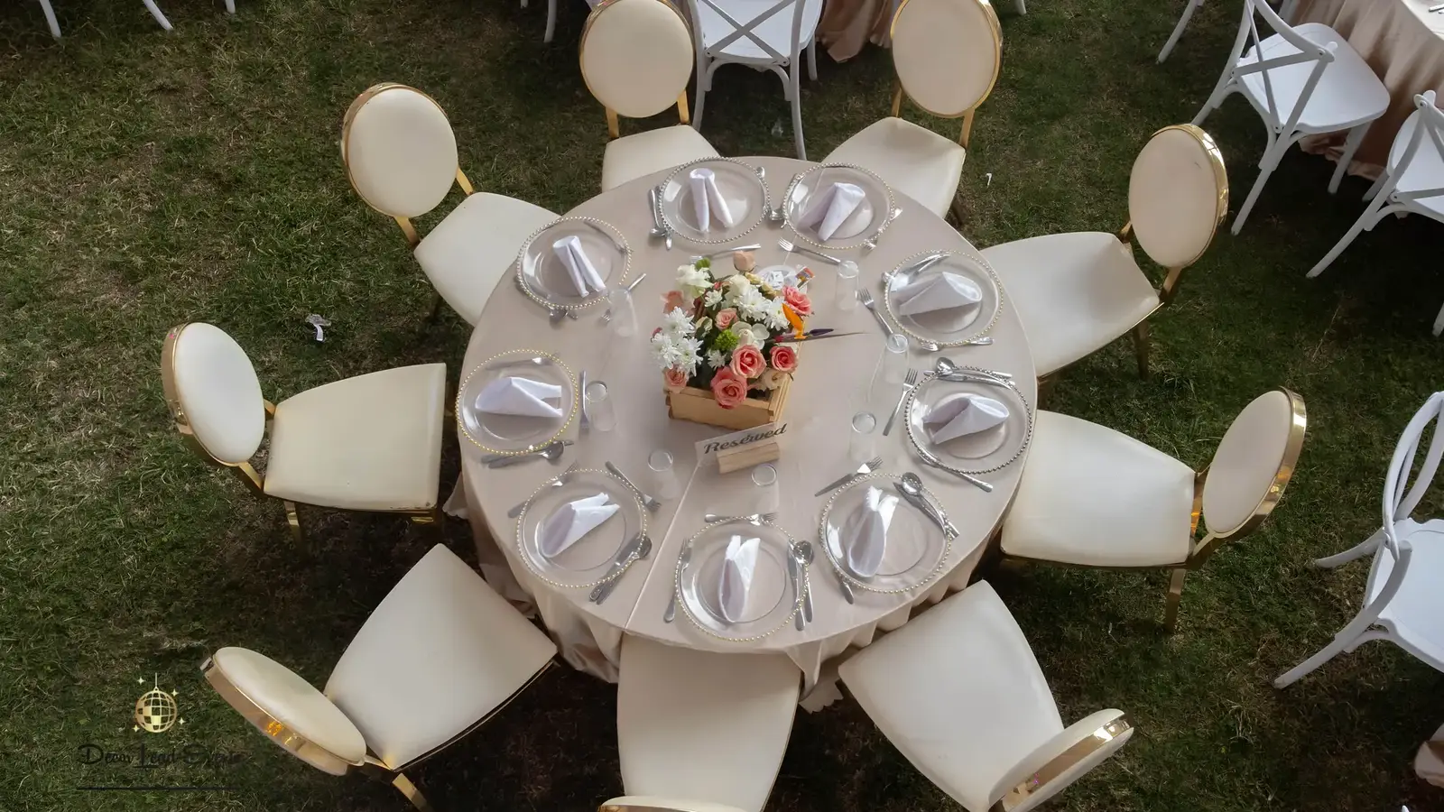 High-angle shot of a round table setting with a beige tablecloth, peach floral centerpiece, and