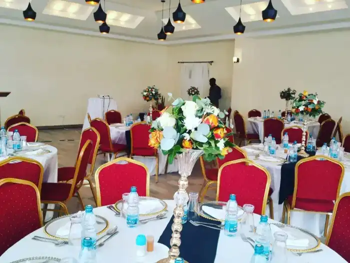 Indoor banquet hall with red banquet chairs, black table runners, and modern pendant lights.