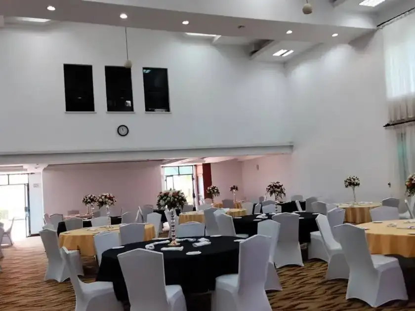 Indoor banquet hall with black and gold tables and white chairs.