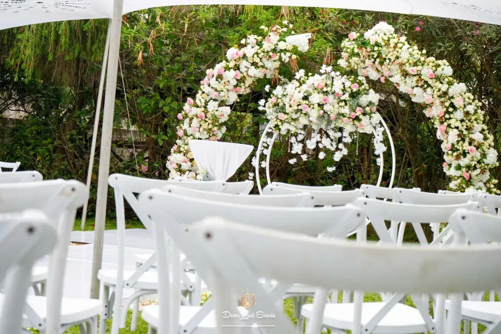 Floral arch and white chairs set for an outdoor ceremony