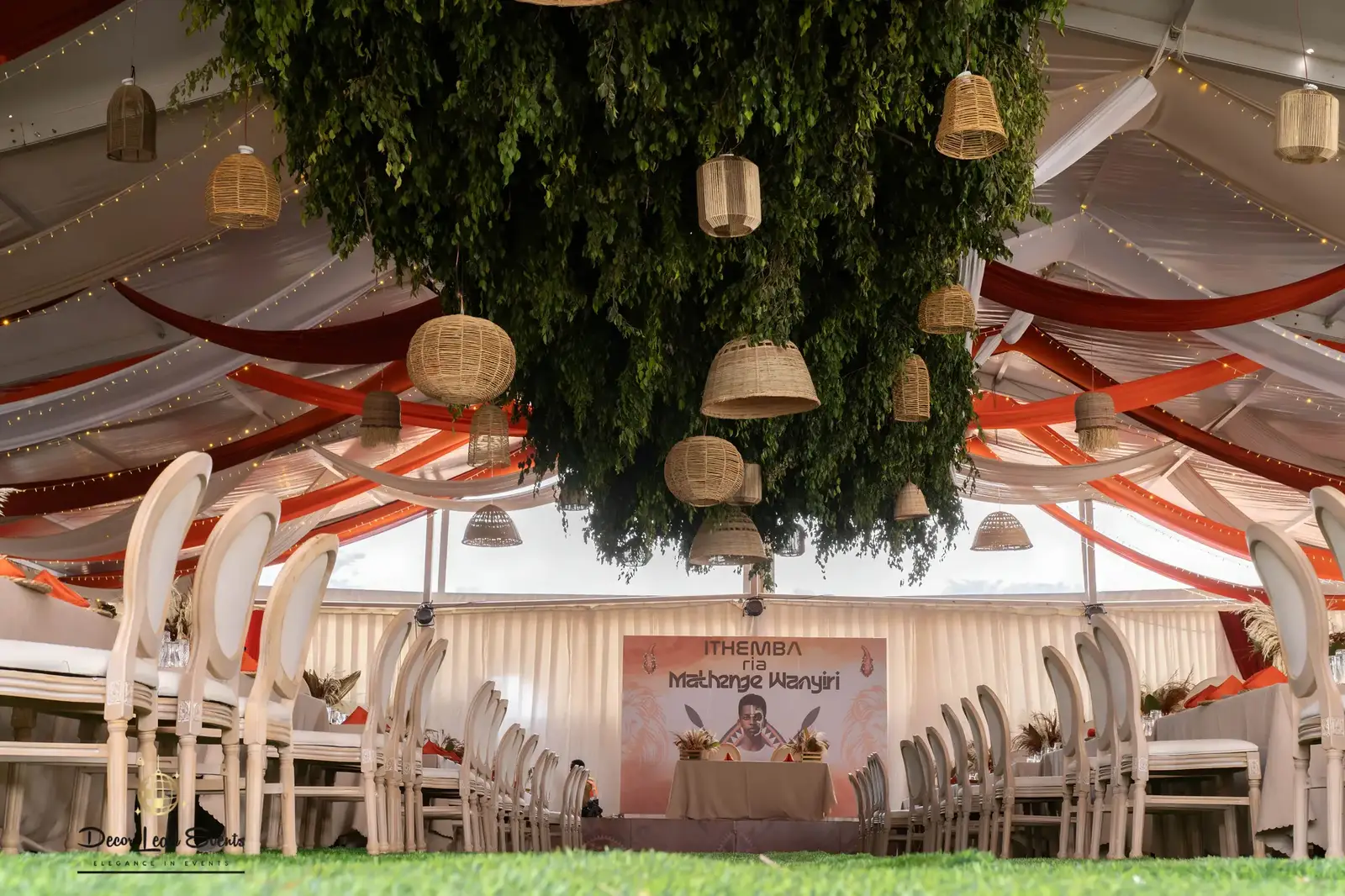 Elaborate ceiling decor inside a tent featuring rust and white drapes, and a large central greenery